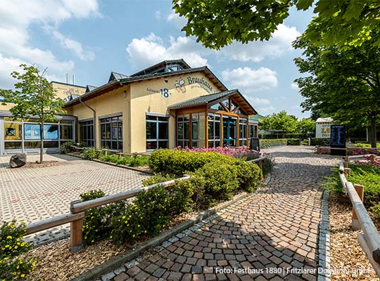 Außenansicht des Festhauses mit gepflasterten Weg vor dem Haus